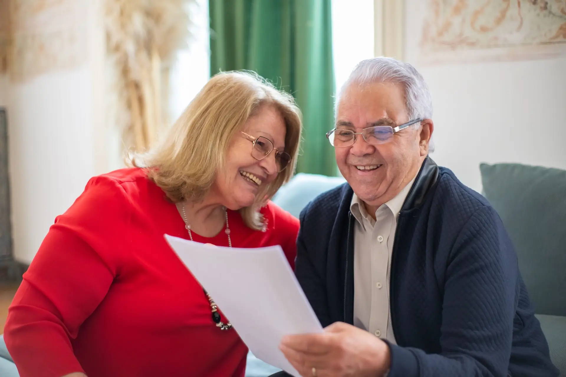 Casal de idosos sorridente lendo documento, representando a isenção de IR por doença grave