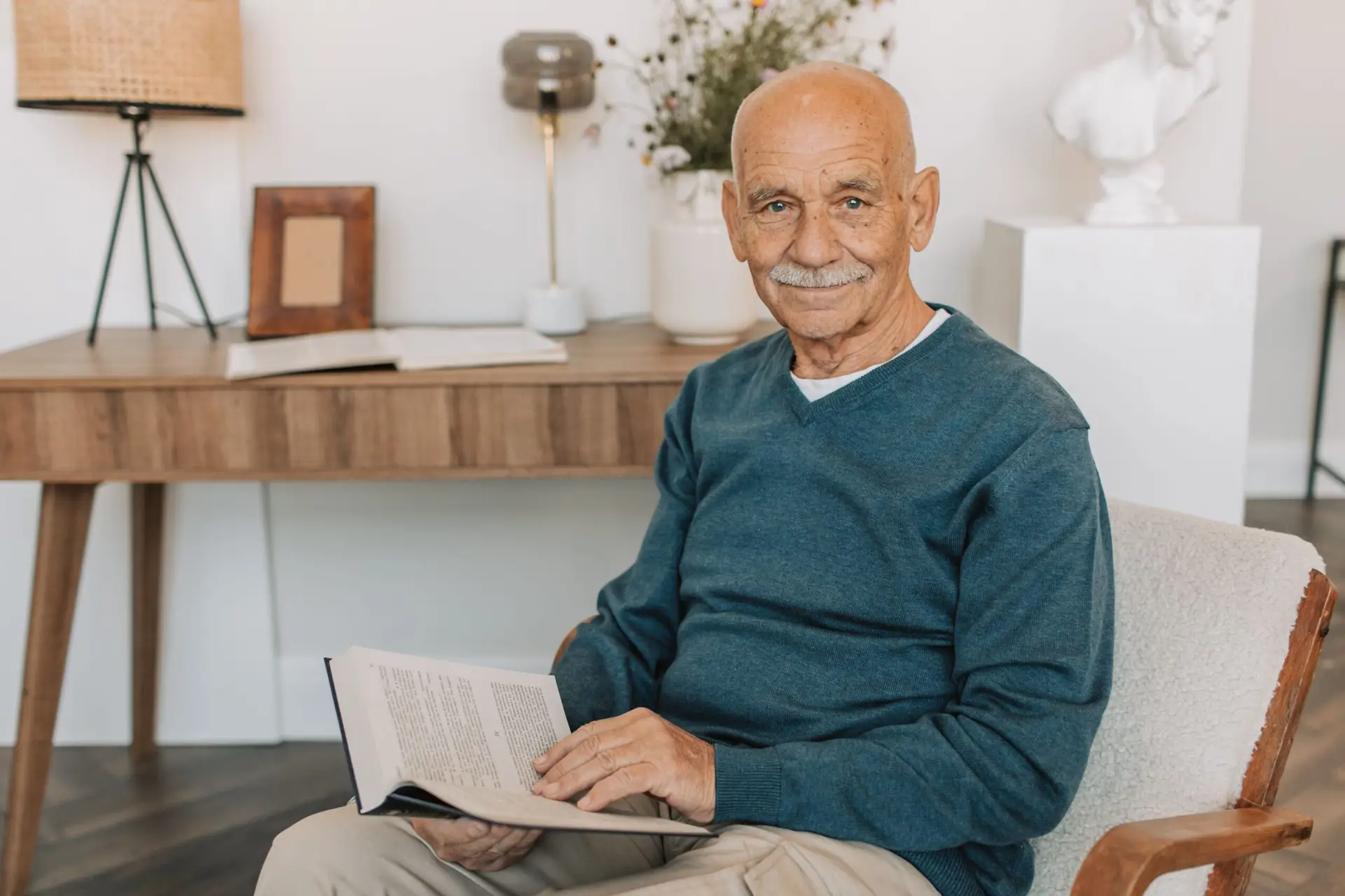 Aposentado sorridente lendo em casa, representando o direito à isenção de Imposto de Renda por câncer